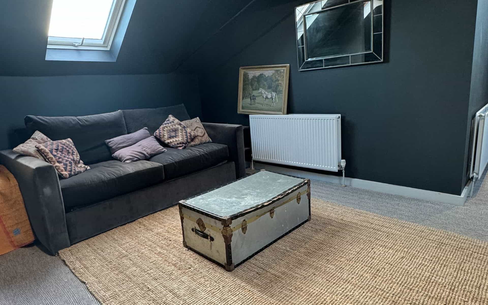 Cosy living room in The Flat, Barn Drift Norfolk with dark walls and vintage trunk coffee table.