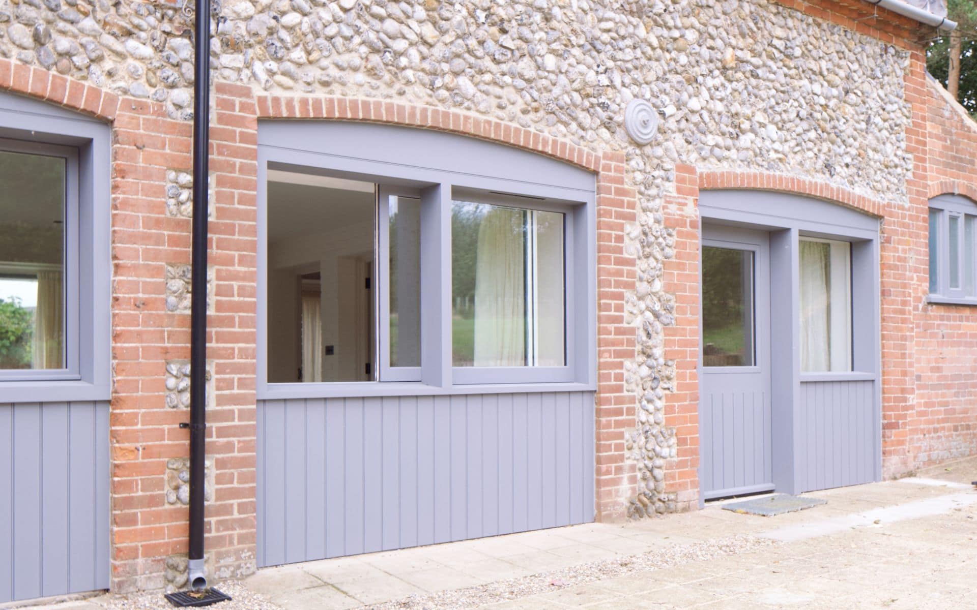 Barn Drift Norfolk stables with grey windows and doors, stone and brick exterior, in The Stables pos.