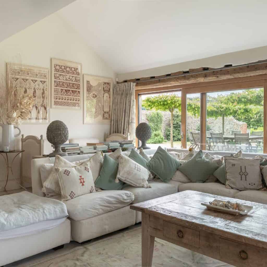Luxury Norfolk accommodation - barn living room with large windows, vintage furniture, and garden view, ideal for relaxing and enjoying rural beauty.