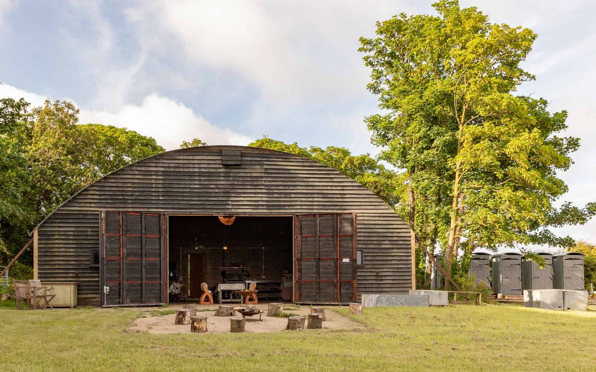 Barn Drift Norfolk barn with open doors, surrounded by lush greenery and outdoor seating, ideal for.
