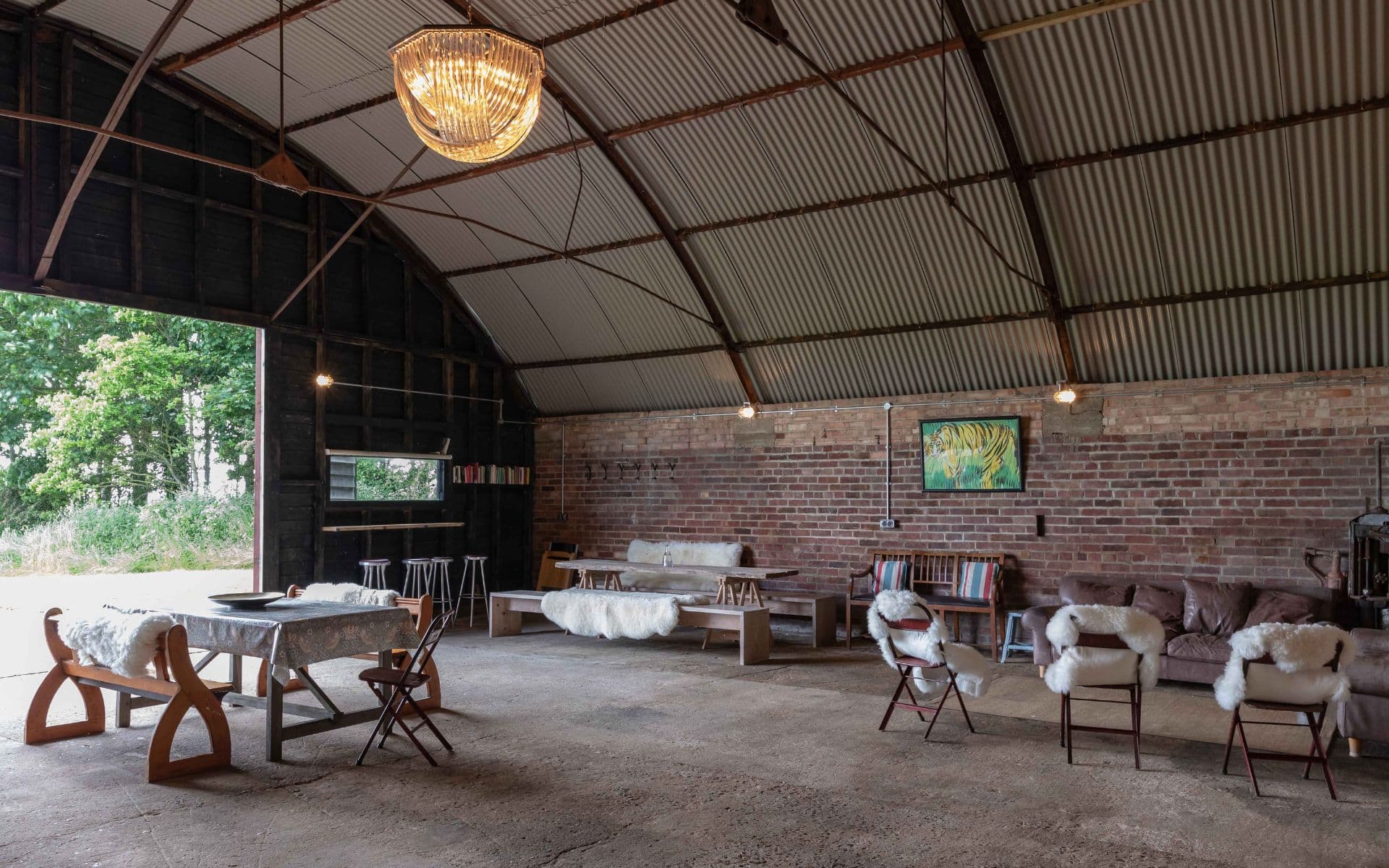 Barn Drift Norfolk interior with rustic furniture and brick walls, under a curved metal roof. Perfec.