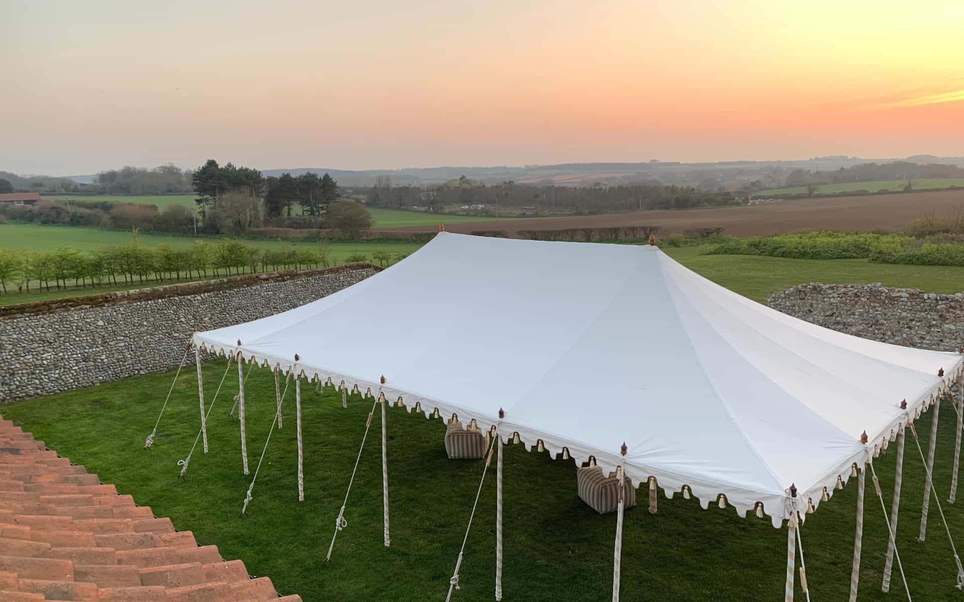 Elegant white wedding marquee set up in a lush green woodland setting at sunset, perfect for woodlan.